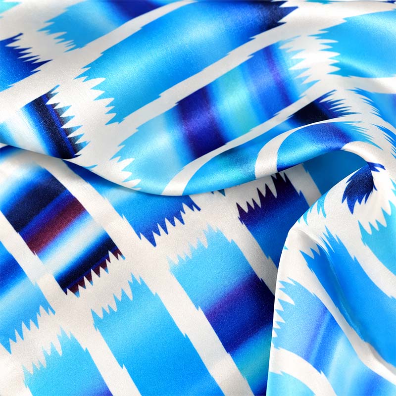 A close-up of of an Ethnic teal and navy large silk satin scarf by Anne Touraine Paris.