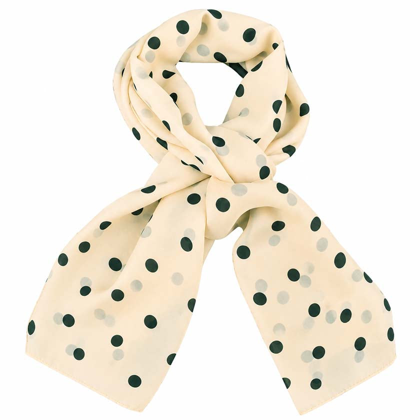 A beige scarf with a black polka dot pattern, styled in a loose knot on a solid white background. By Anne Touraine Paris.