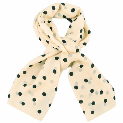 A beige scarf with a black polka dot pattern, styled in a loose knot on a solid white background. By Anne Touraine Paris.
