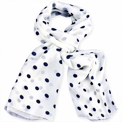 A white silk chiffon scarf with black polka dots, by Anne Touraine Paris, styled in a loop with a knot on a plain white background.