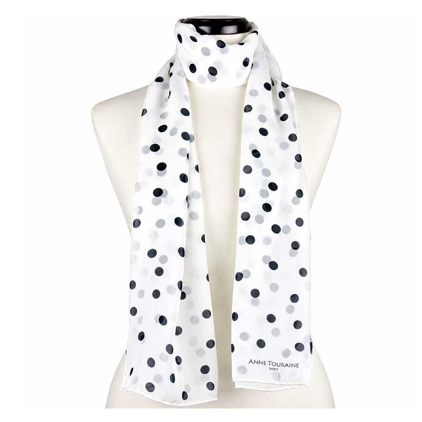 A white silk chiffon scarf with black polka dots, by Anne Touraine Paris, styled on a mannequin on a plain white background.